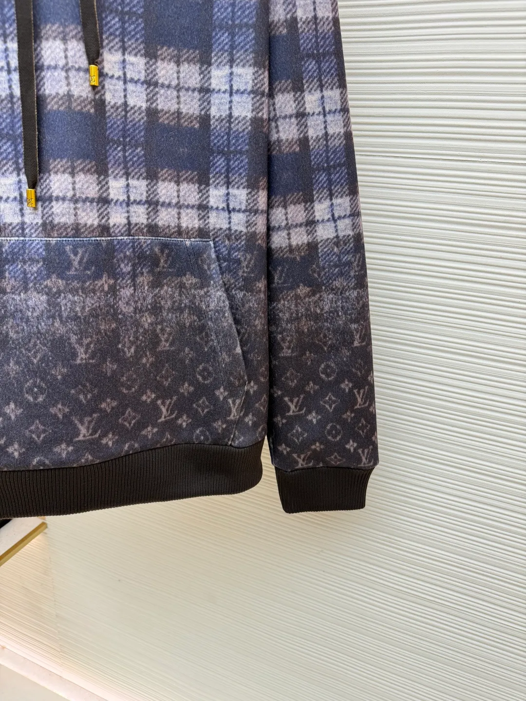 LOUIS VUITTON plaid gradient long-sleeved hoodie ●Original version: Purchased and developed for 15100 ●Item number: 1681896-B40 ●Fabric: wool blended fabric ●Technology: Digital direct printing ●Color: Purple ●Version: Fitted version ●Weight: about 1035 grams ●Size: S-M-L-XL ●Description: This hooded sweatshirt uses splicing technology to create a layered texture: the upper part is made of wool blended fabric with a blue and gray plaid pattern, and is pre-shrunk to ensure a stable fit; the lower part and sleeves use digital printing technology to present a gradient Monogram dark pattern, and the ink penetrates the fiber to achieve high color fastness. The hood has a built-in invisible lining to enhance stiffness, and the drawstring is made of wear-resistant nylon rope with a metal bell for smooth pulling. The front kangaroo pocket is made of welted bag technology, and the edge of the bag mouth is reinforced with double stitching. The cuffs and hem are made of ribbed knitted fabric, and the elastic hemming fits the body shape. The seams throughout the garment are high-strength stitches of the same color. Precision sewing every 3cm/12 stitches improves durability. The overall craftsmanship takes into account both visual details and practical durability. The overall wiring is straight and delicate, the fabric is comfortable and soft, and the color is consistent without color difference. It can be matched with the same style to create a fashionable look and control various occasions. Customized accessories, complete with three standards, same style for men and women!